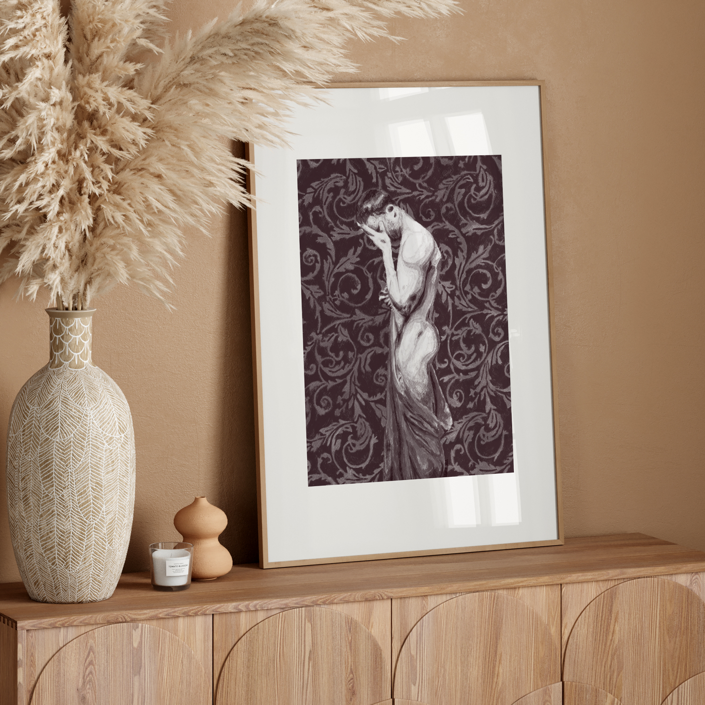 Decorative setup with a vase, dried plants, and framed artwork on a wooden console against a beige wall.