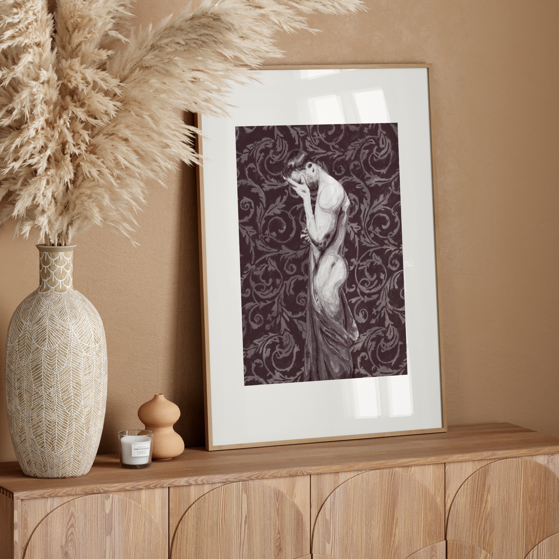 Decorative setup with a vase, dried plants, and framed artwork on a wooden console against a beige wall.