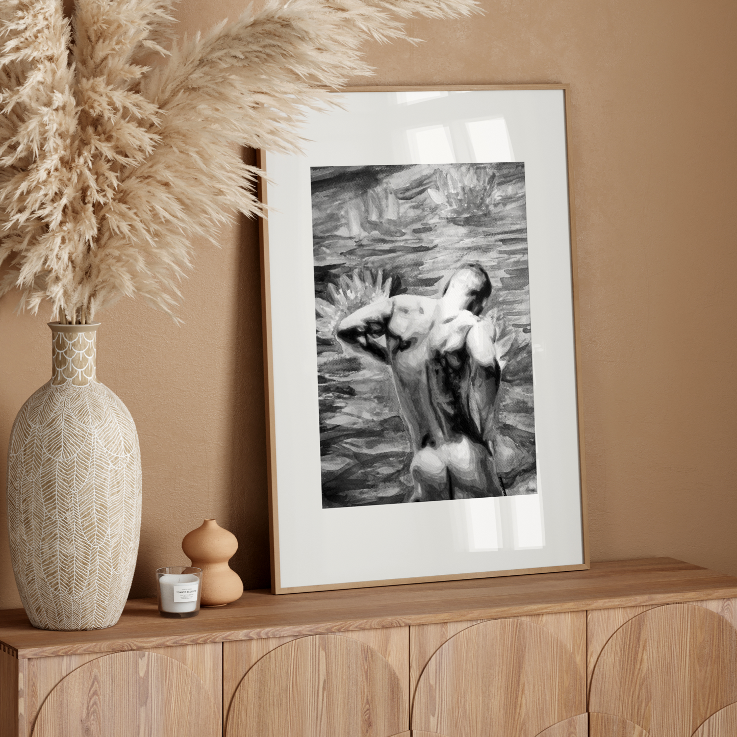 Framed black and white artwork on a wooden sideboard with decorative vase and pampas grass.