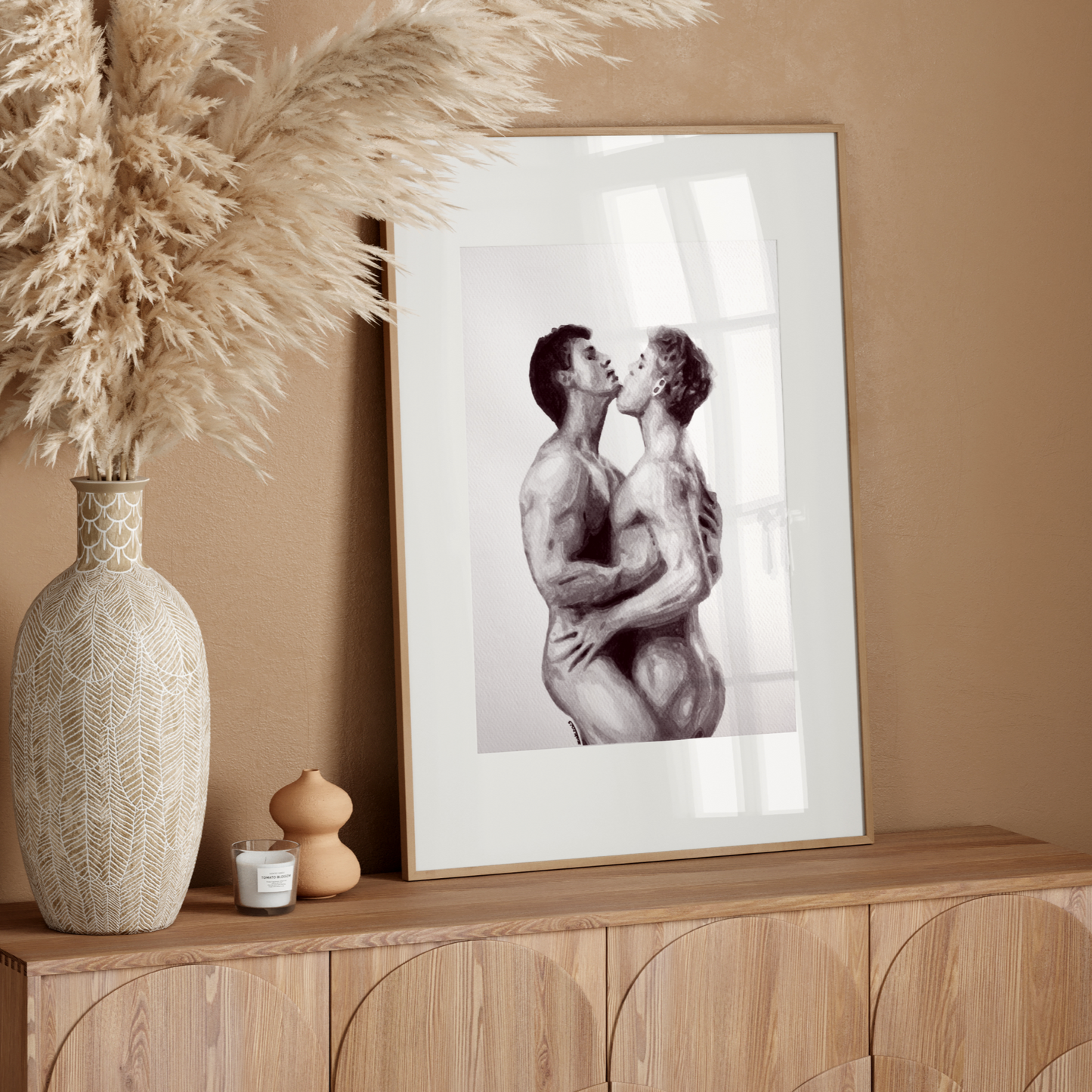 Framed black and white artwork of two people embracing on a wooden sideboard with decorative vase and candle.