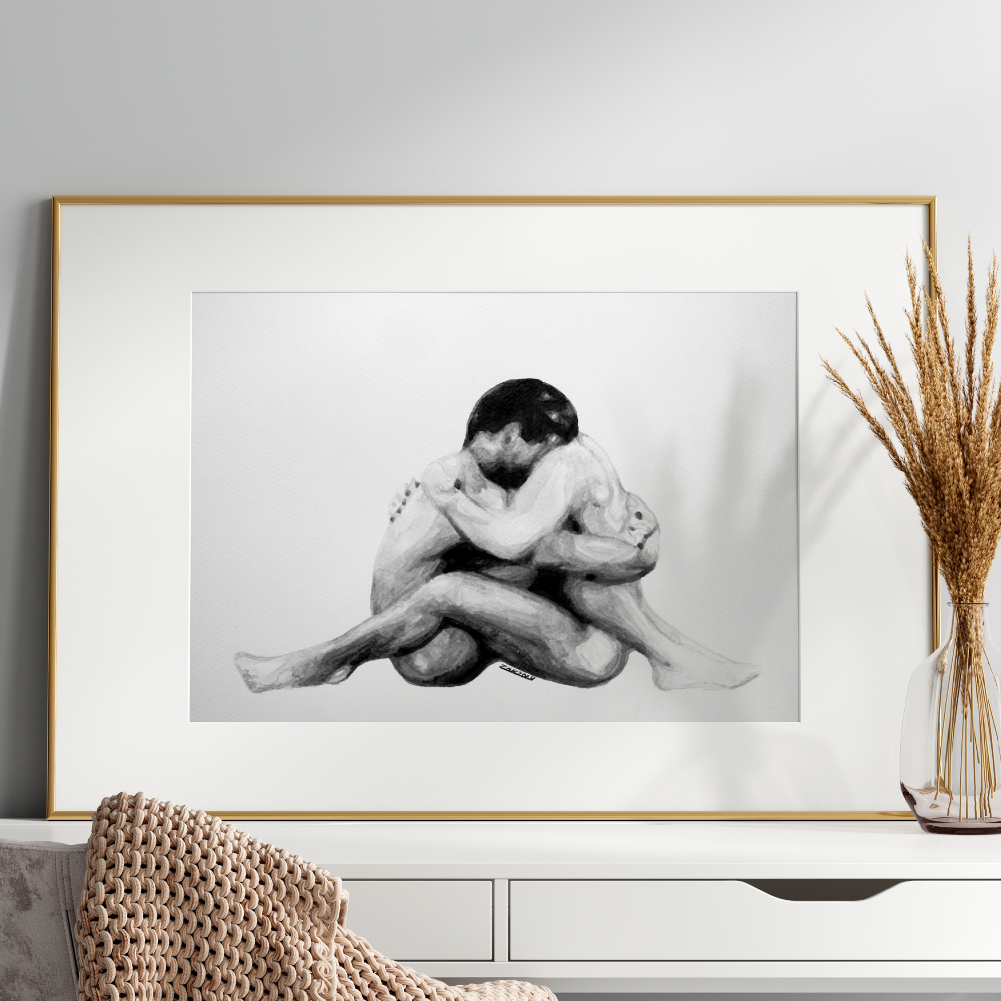 Framed black and white artwork of two people embracing on a wall above a white console table.