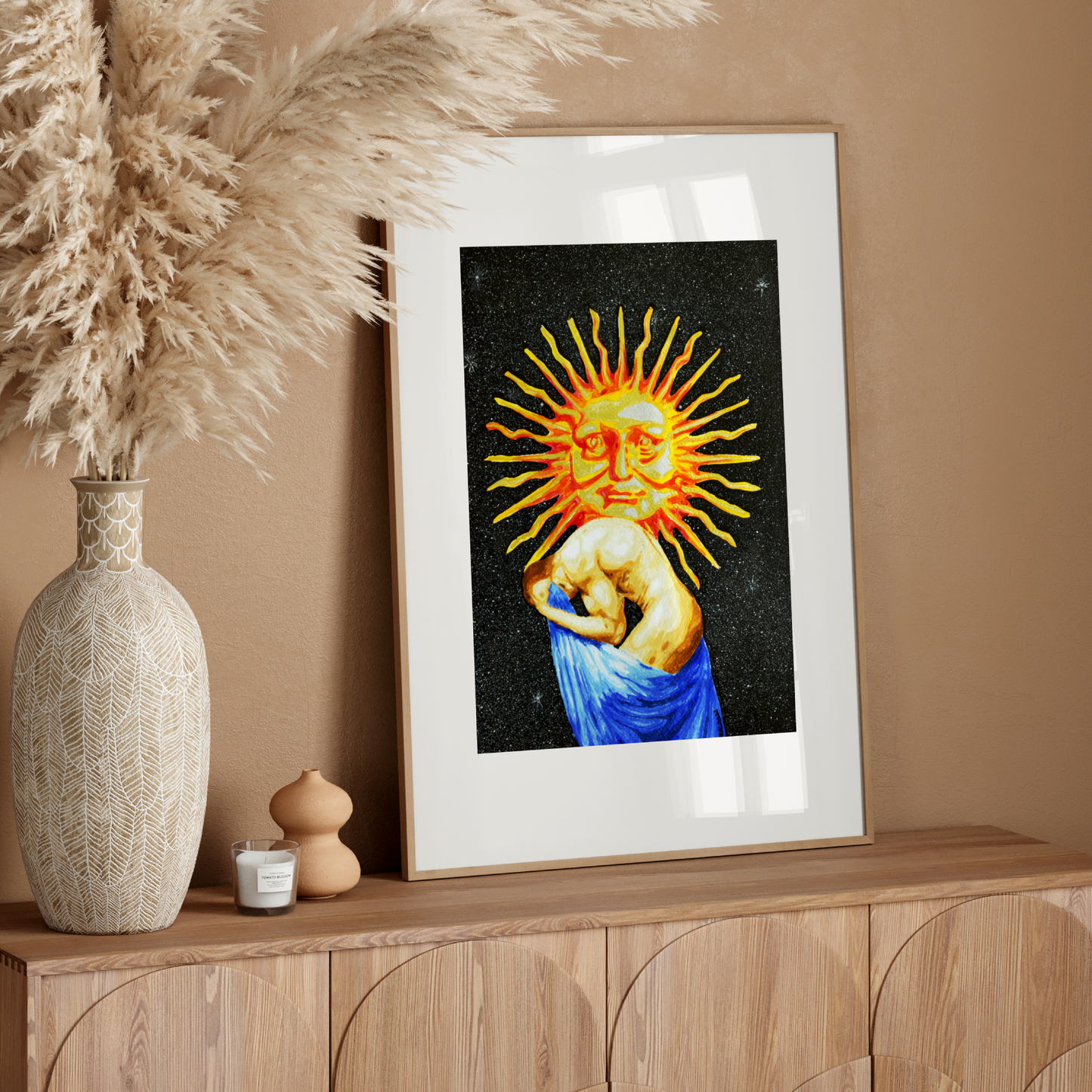 Framed artwork of a sun god on a wooden console table with decorative elements.