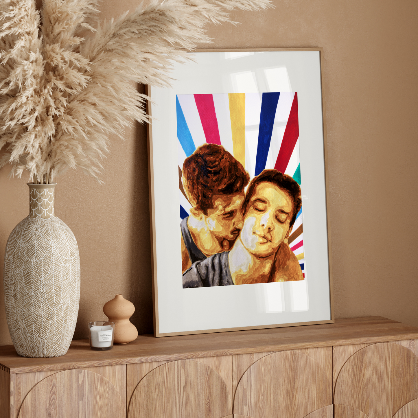 Framed artwork of a couple embracing with colorful abstract design on a wooden sideboard against a beige wall.