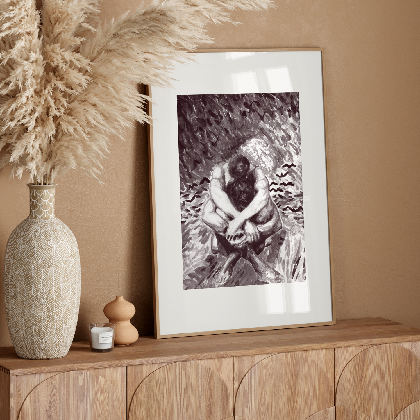 Framed artwork on a wooden console table with decorative elements against a beige wall.