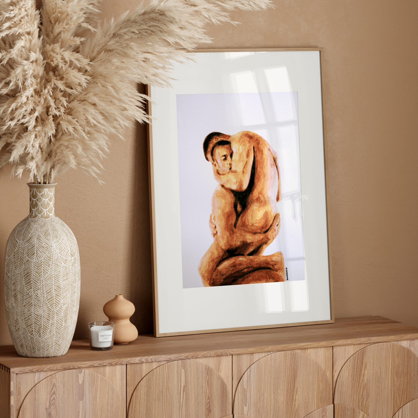 Framed artwork on a wooden console table with decorative elements against a beige wall.