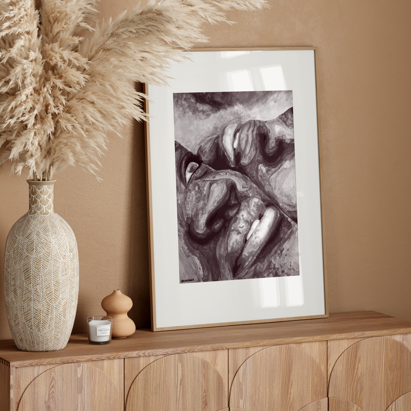 Decorative setup with a vase, dried plants, and framed artwork on a wooden console against a beige wall.