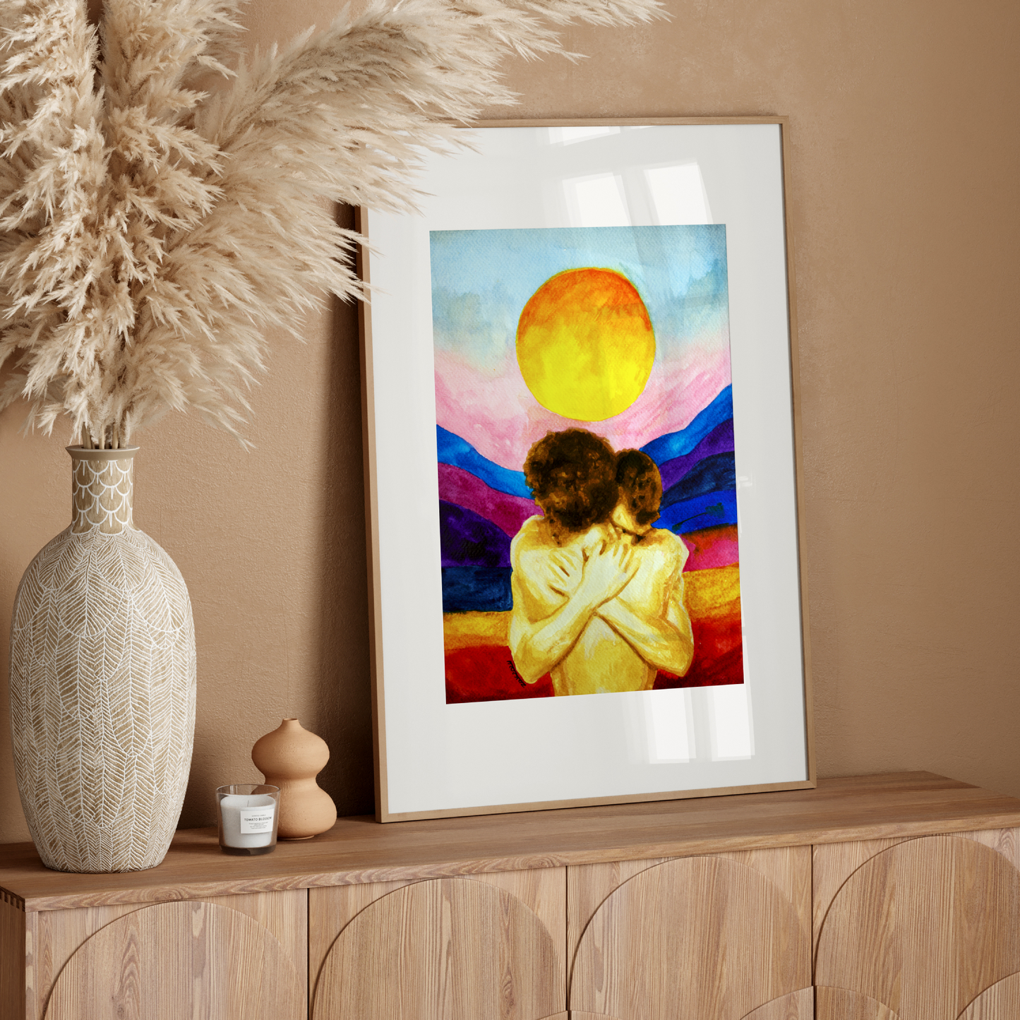 Framed artwork of a couple embracing with a colorful background on a wooden sideboard.