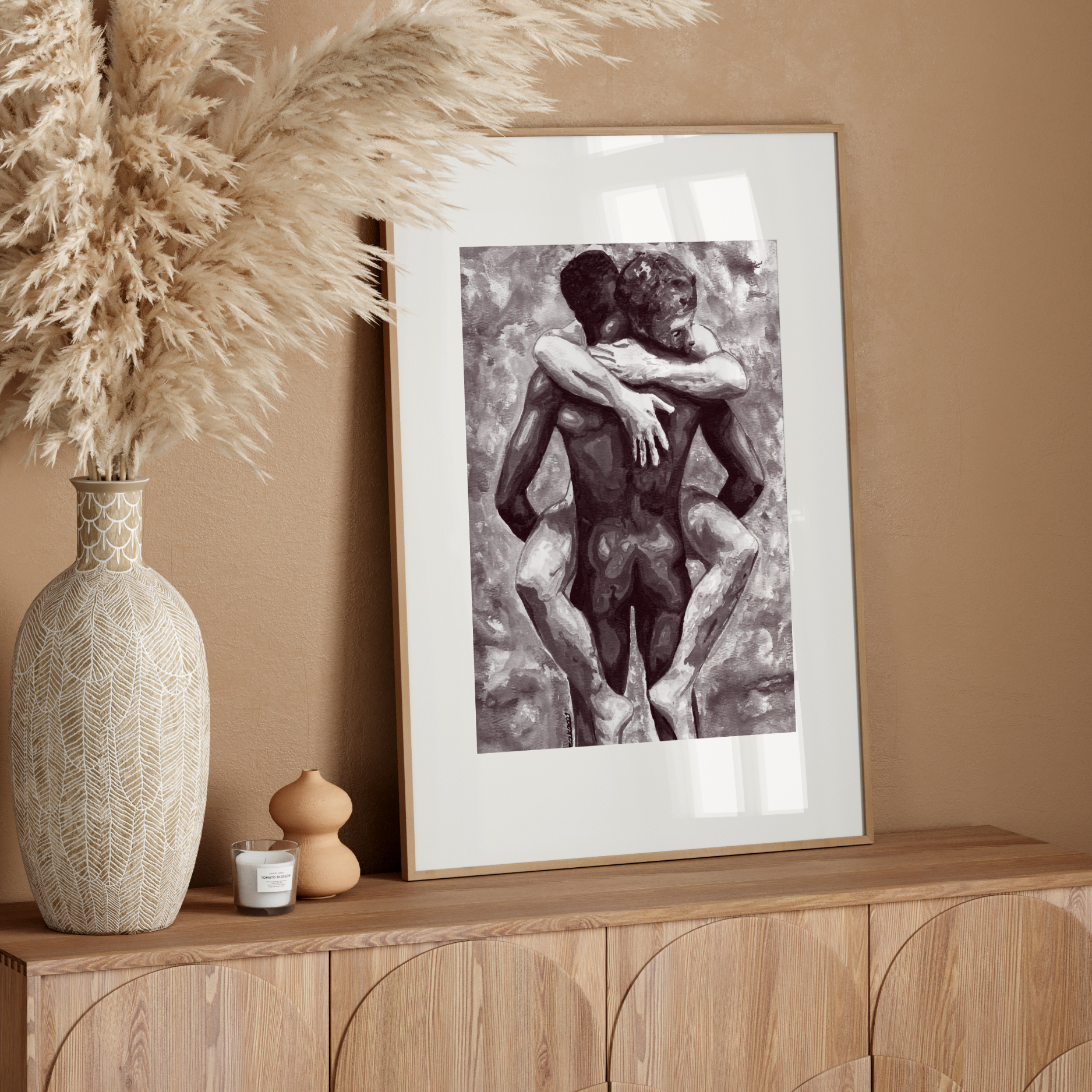 Framed artwork of two embracing figures on a wooden sideboard with decorative vase and pampas grass.