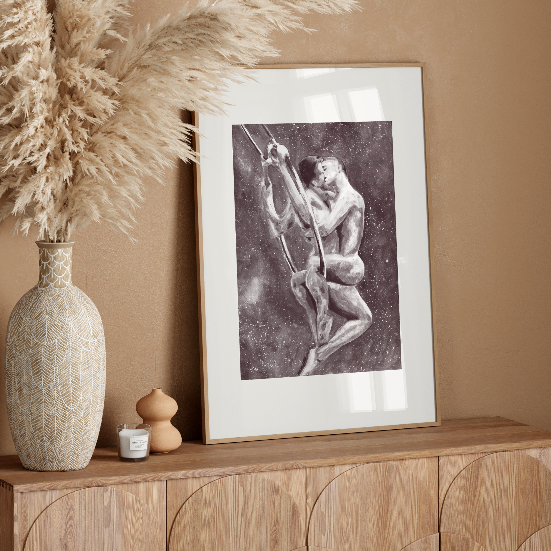 Framed artwork on a wooden console table with decorative elements against a beige wall.