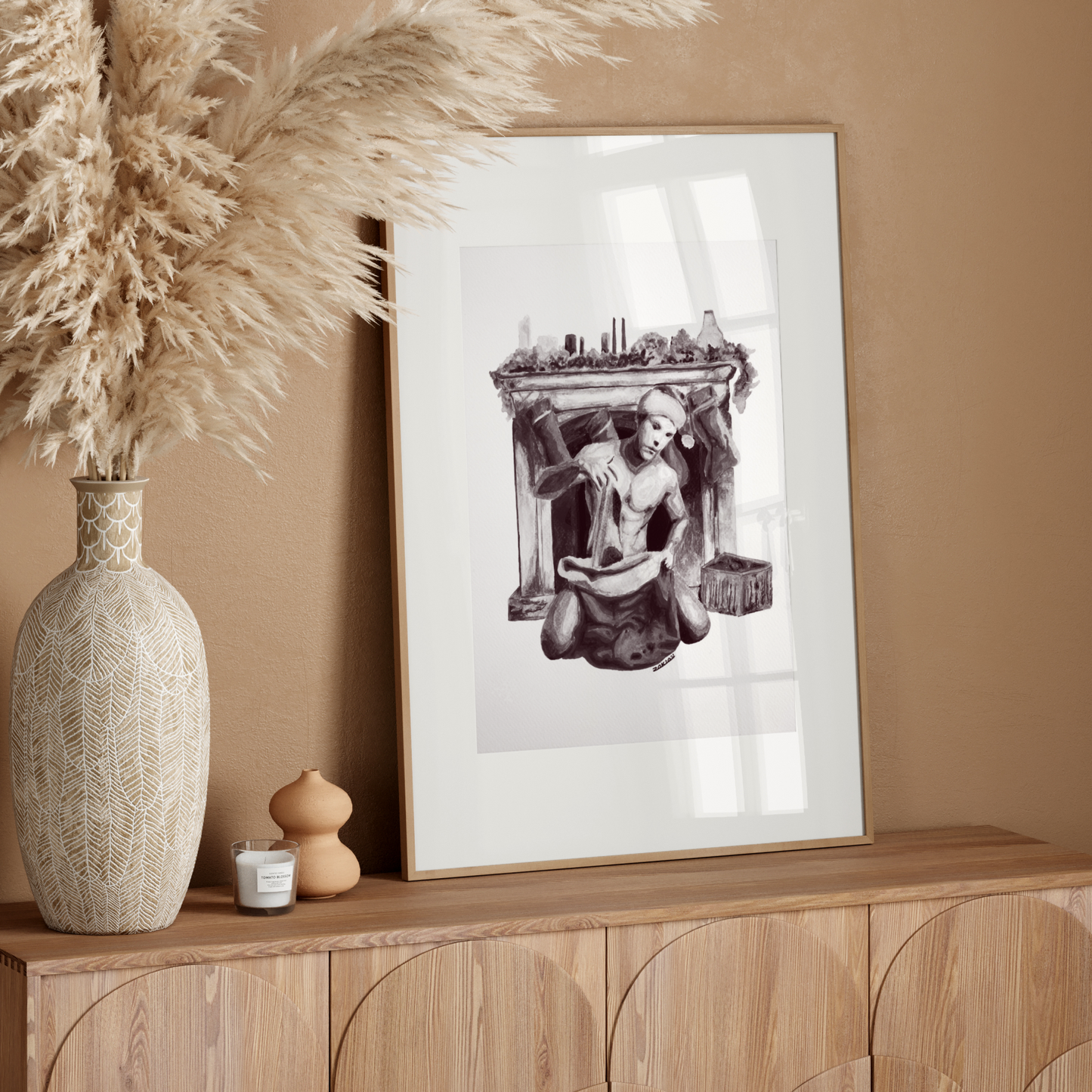 Decorative setup with a vase, candle, and framed artwork on a wooden console against a beige wall.