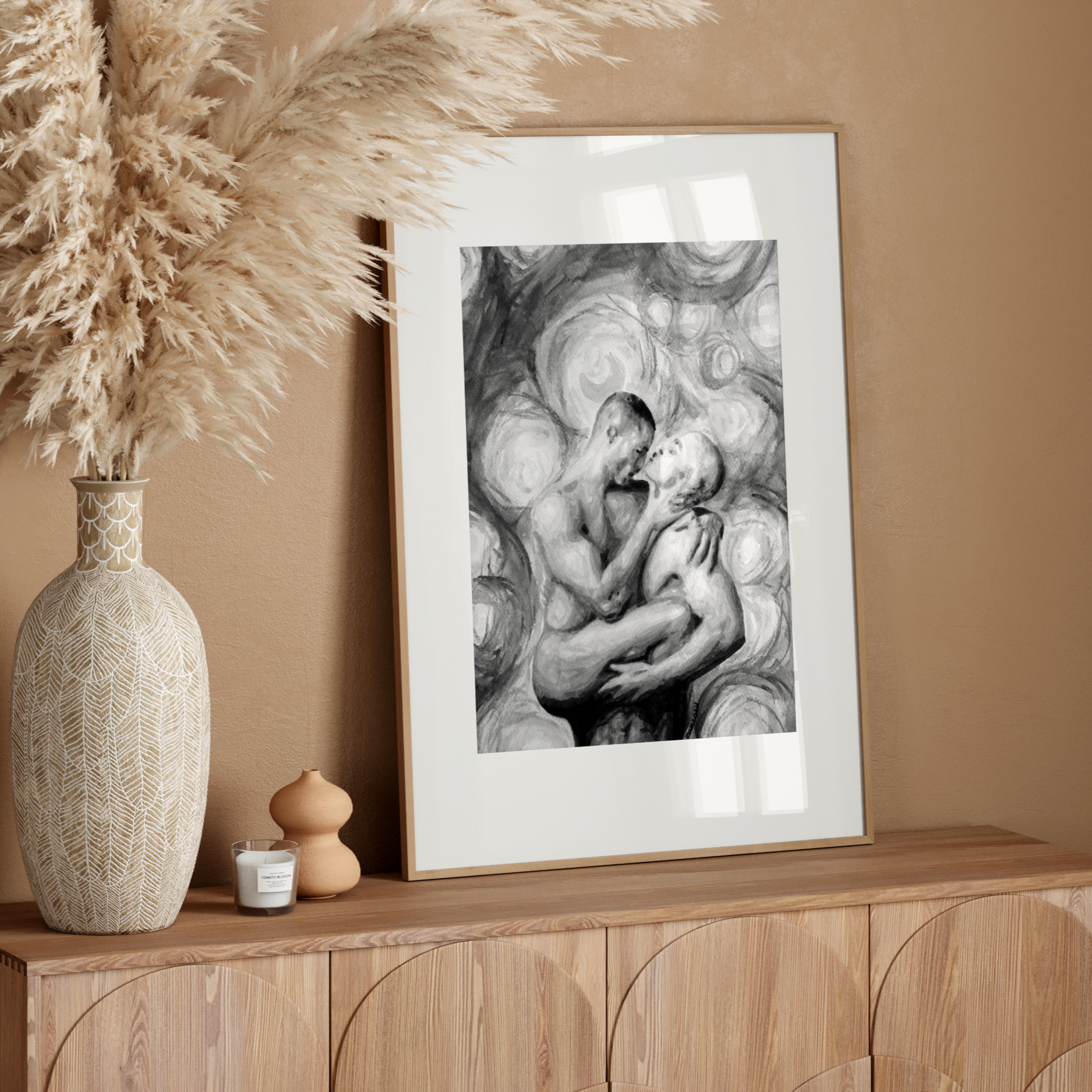 Framed artwork on a wooden sideboard with decorative vase and pampas grass.