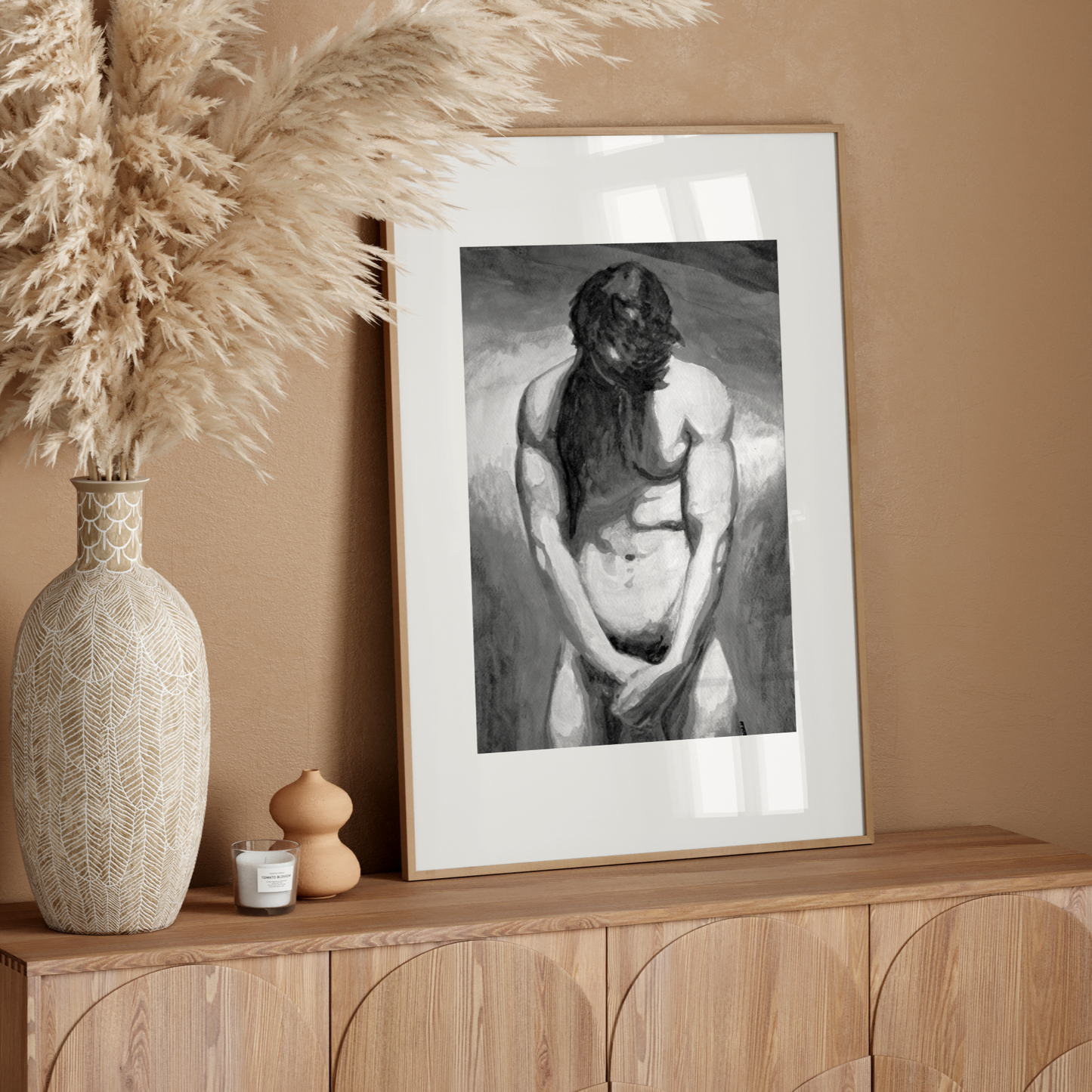 Framed artwork on a wooden console table with decorative elements against a beige wall.