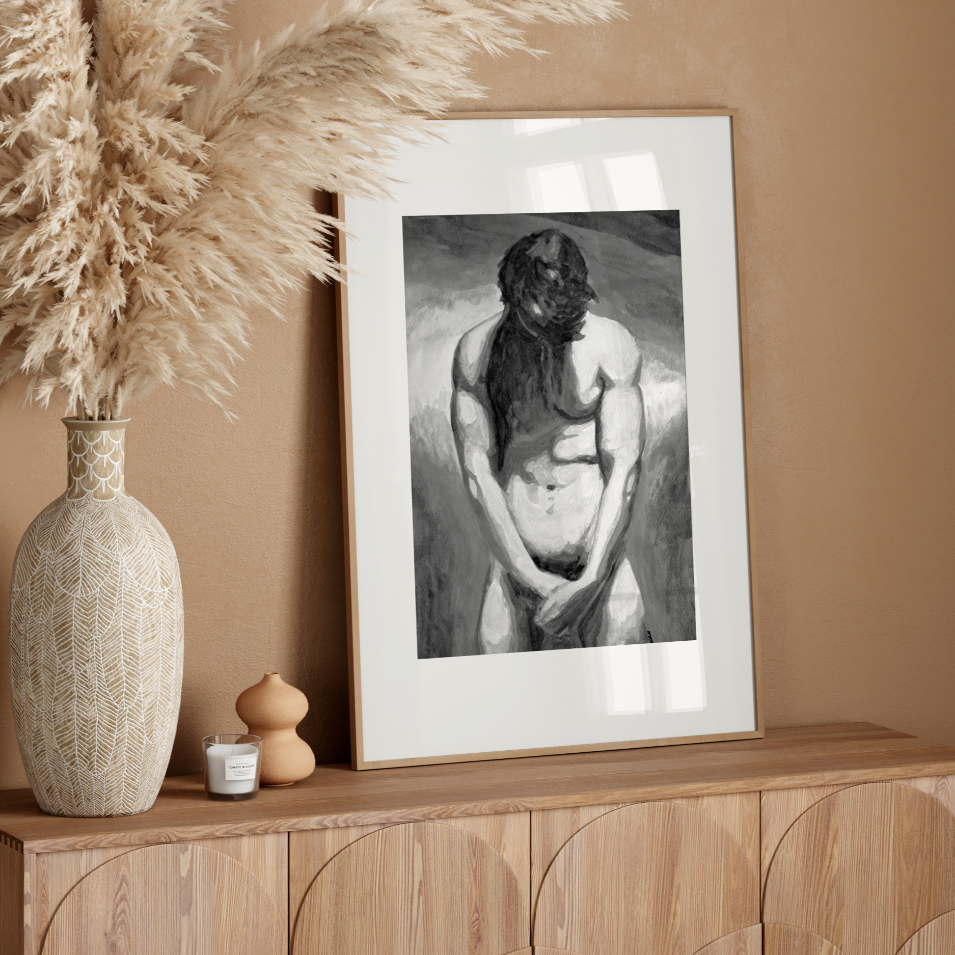 Framed artwork on a wooden console table with decorative elements against a beige wall.