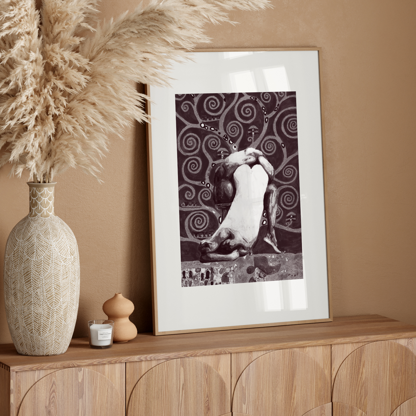 Framed artwork on a wooden console table with decorative elements against a beige wall.