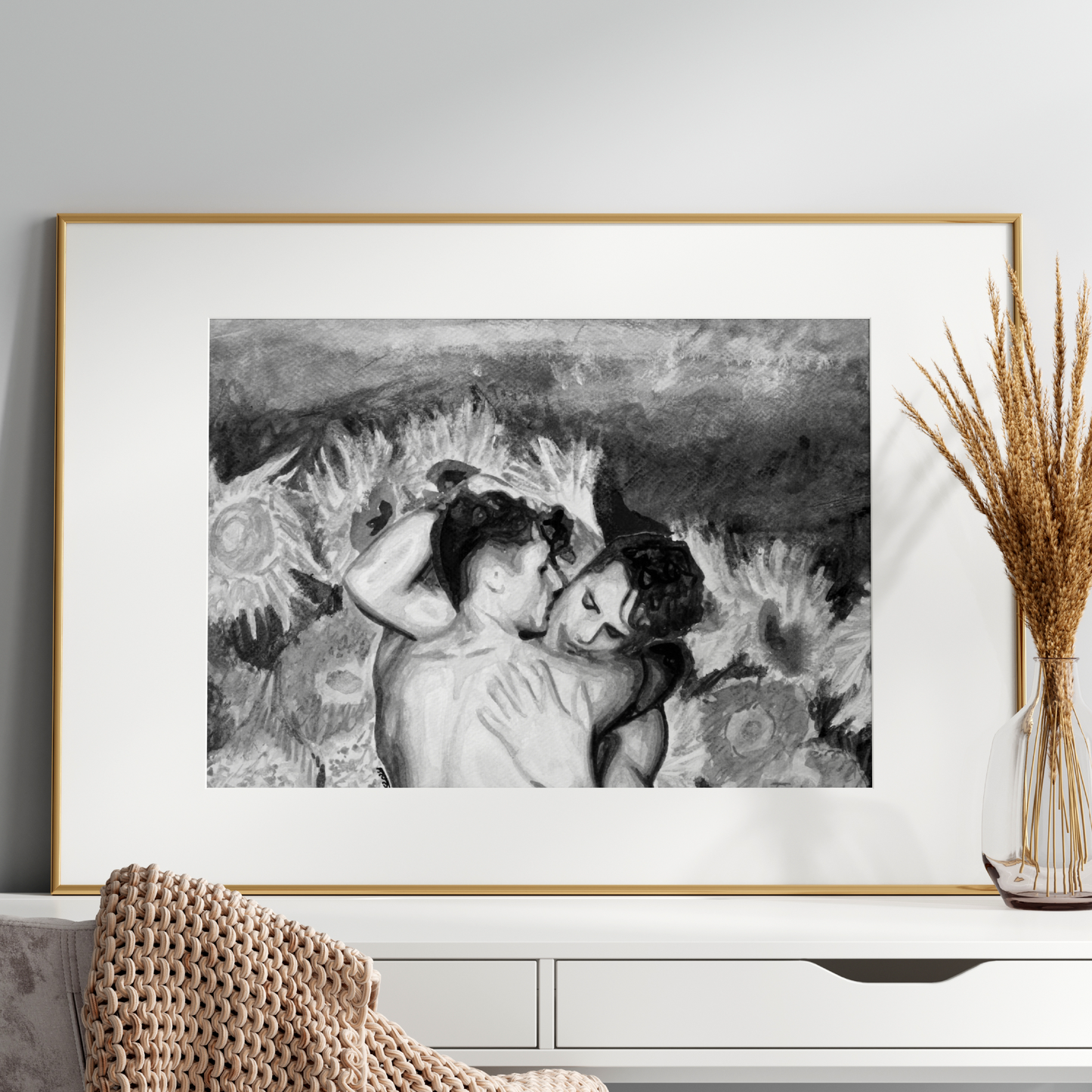 Framed black and white artwork of two people embracing on a white wall above a white console table.