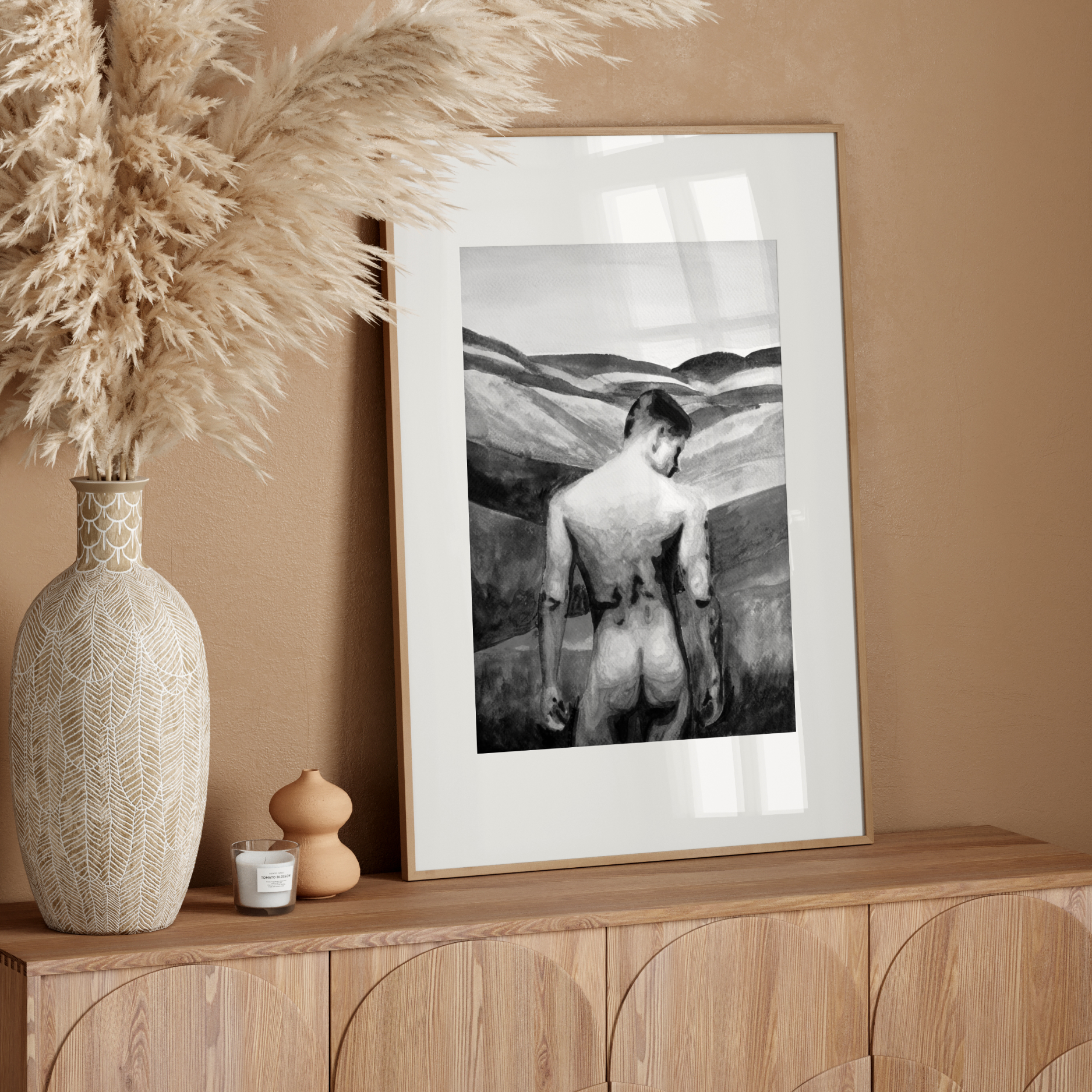Framed artwork on a wooden sideboard with decorative vase and pampas grass.