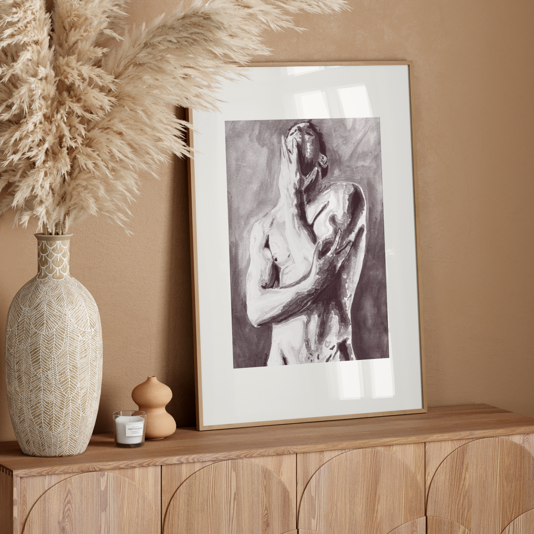 Decorative setup with a vase, framed artwork, and pampas grass on a wooden console against a beige wall.