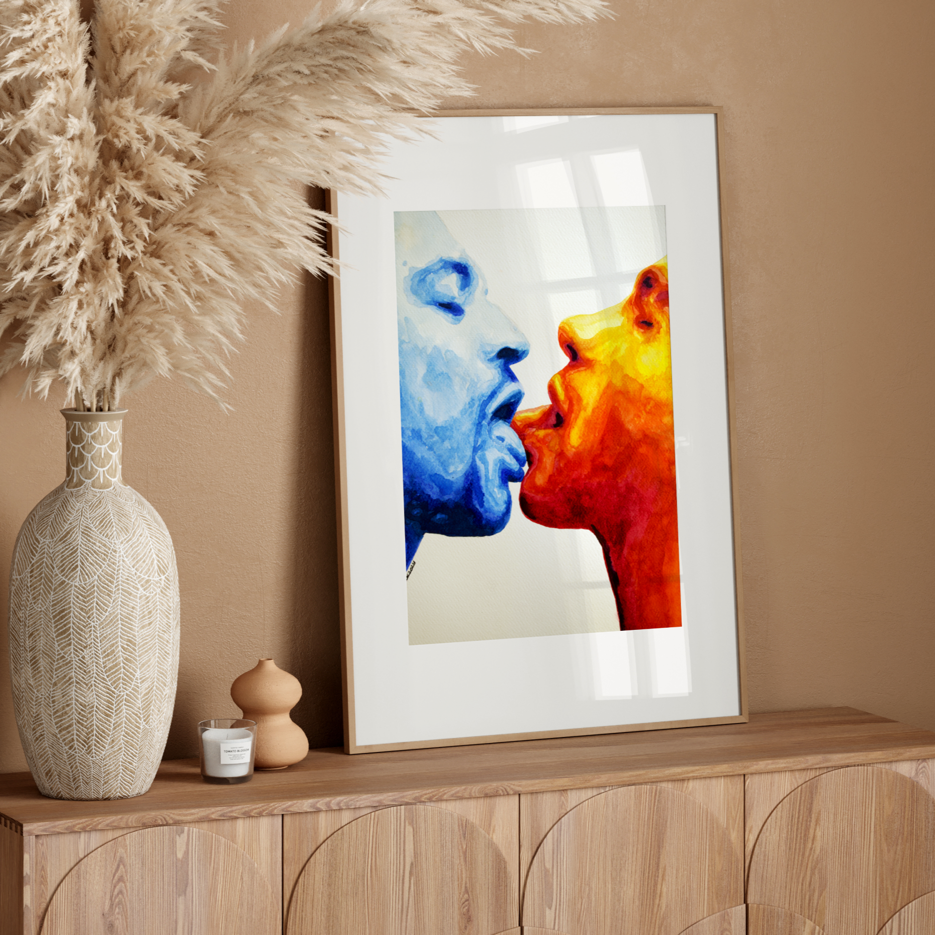 Decorative setup with a vase, candle, and colorful abstract art on a wooden console against a beige wall.