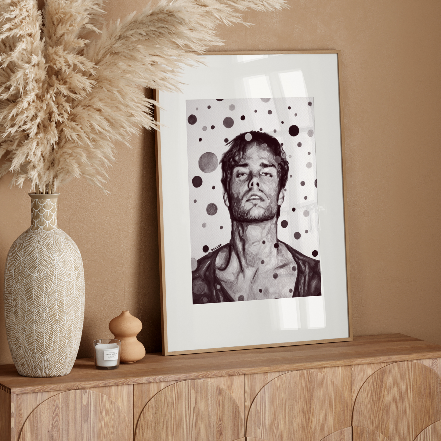 Framed black and white portrait on a wooden sideboard with decorative vase and pampas grass.