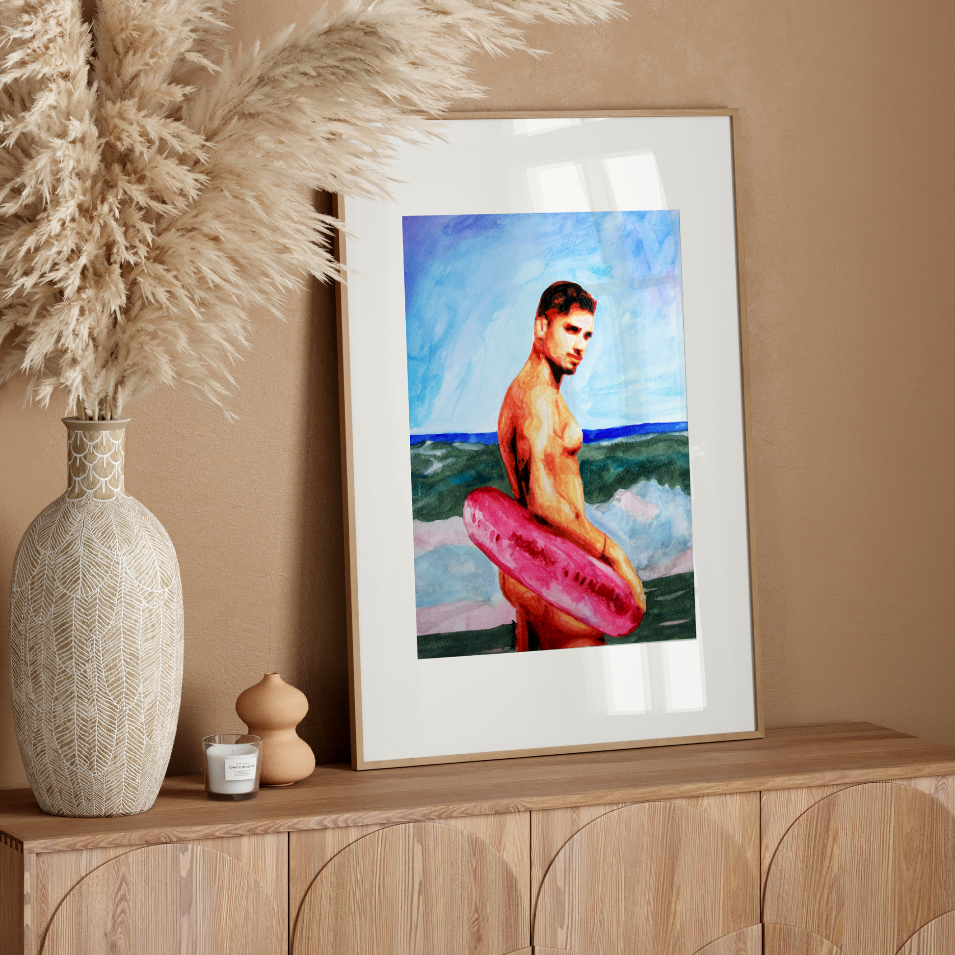 Framed artwork of a man with a surfboard on a wooden sideboard with decorative items.