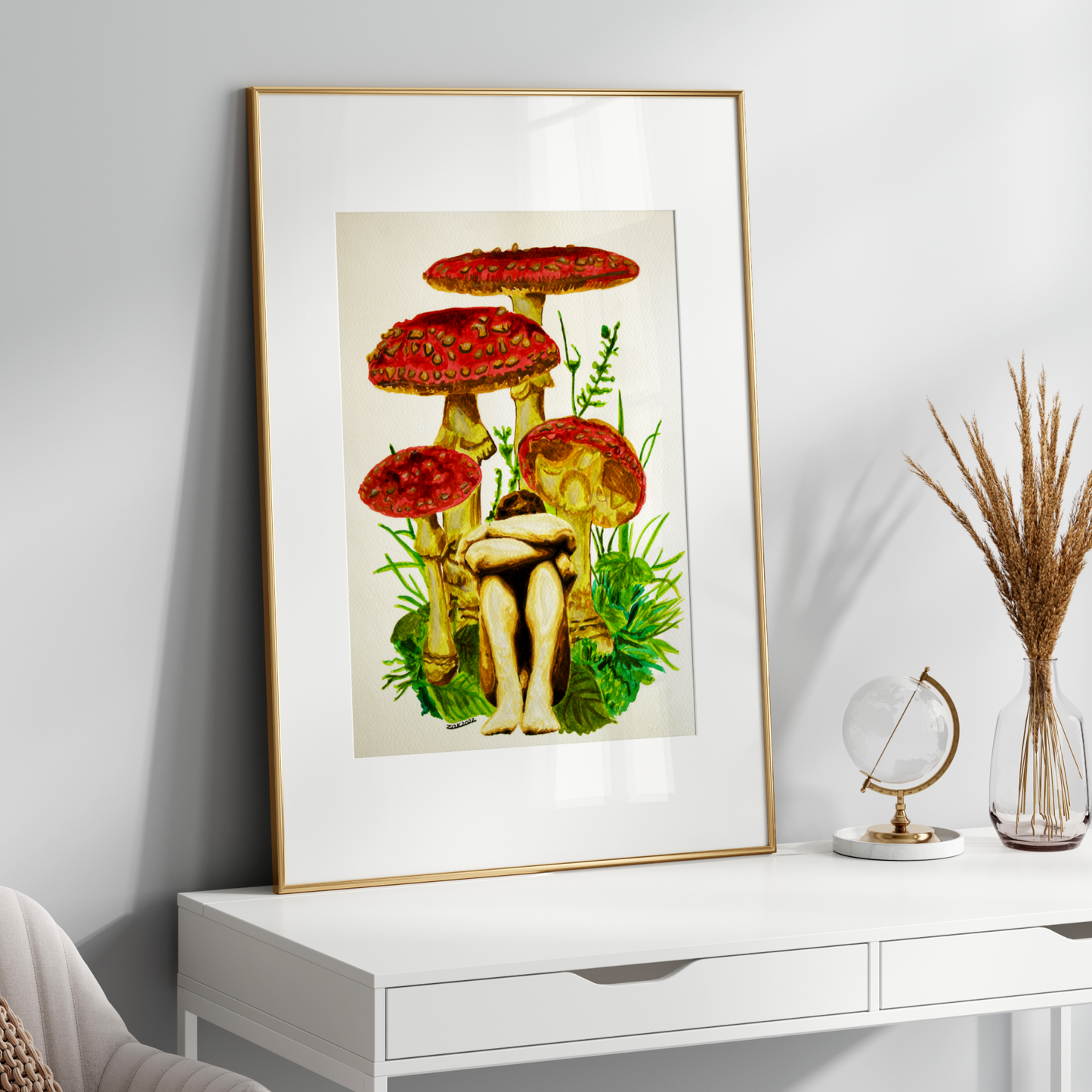 Framed artwork of mushrooms on a white wall above a desk.