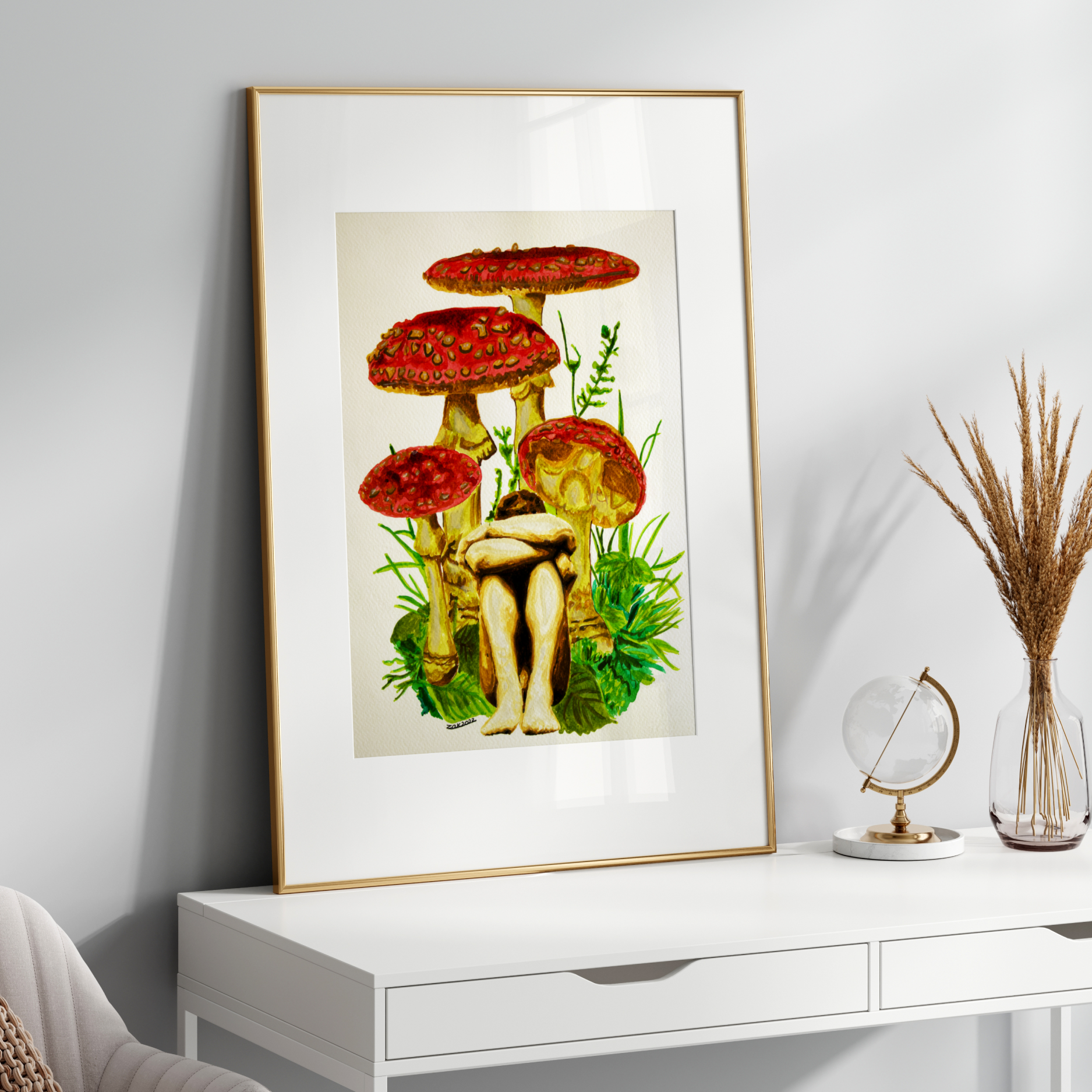 Framed artwork of mushrooms on a white wall above a desk.