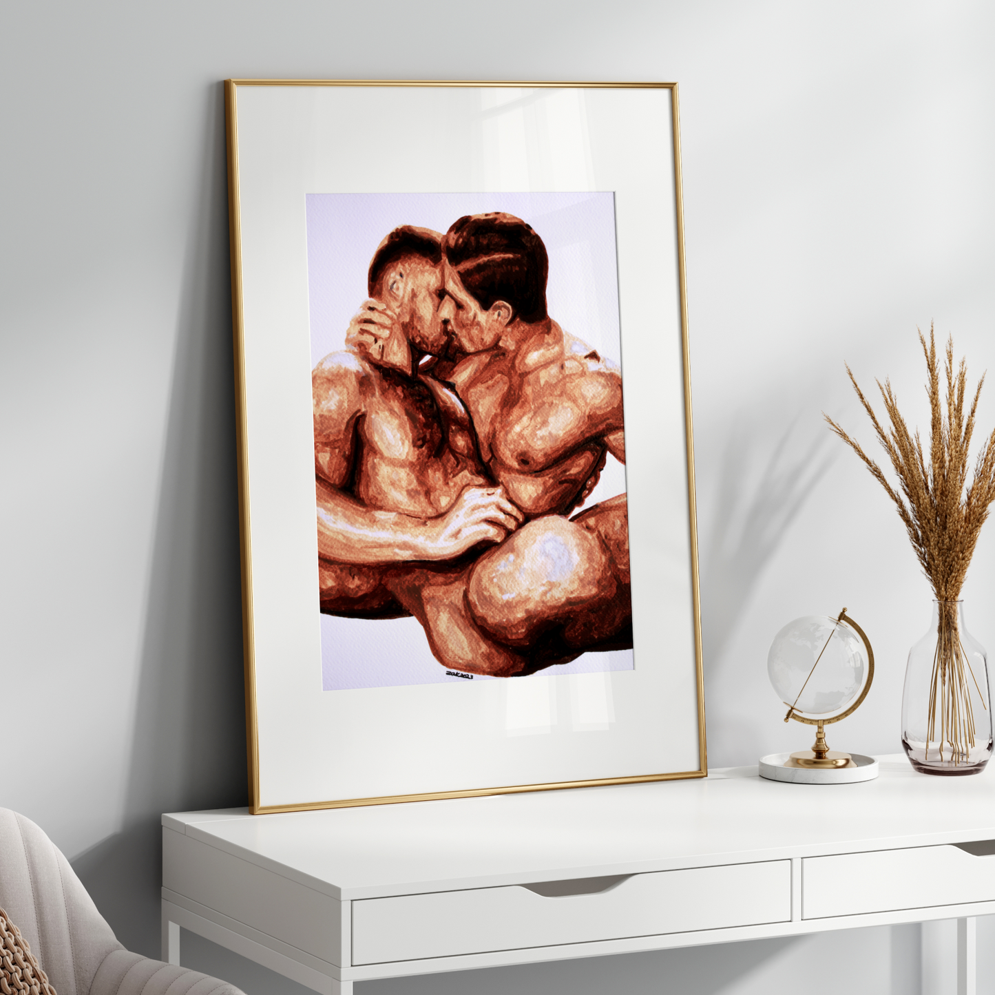 Framed artwork of two muscular men embracing on a white console table with decorative items.