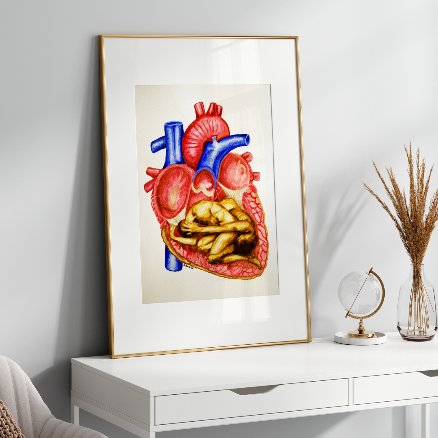 Framed artwork of a colorful heart on a white wall above a white desk.