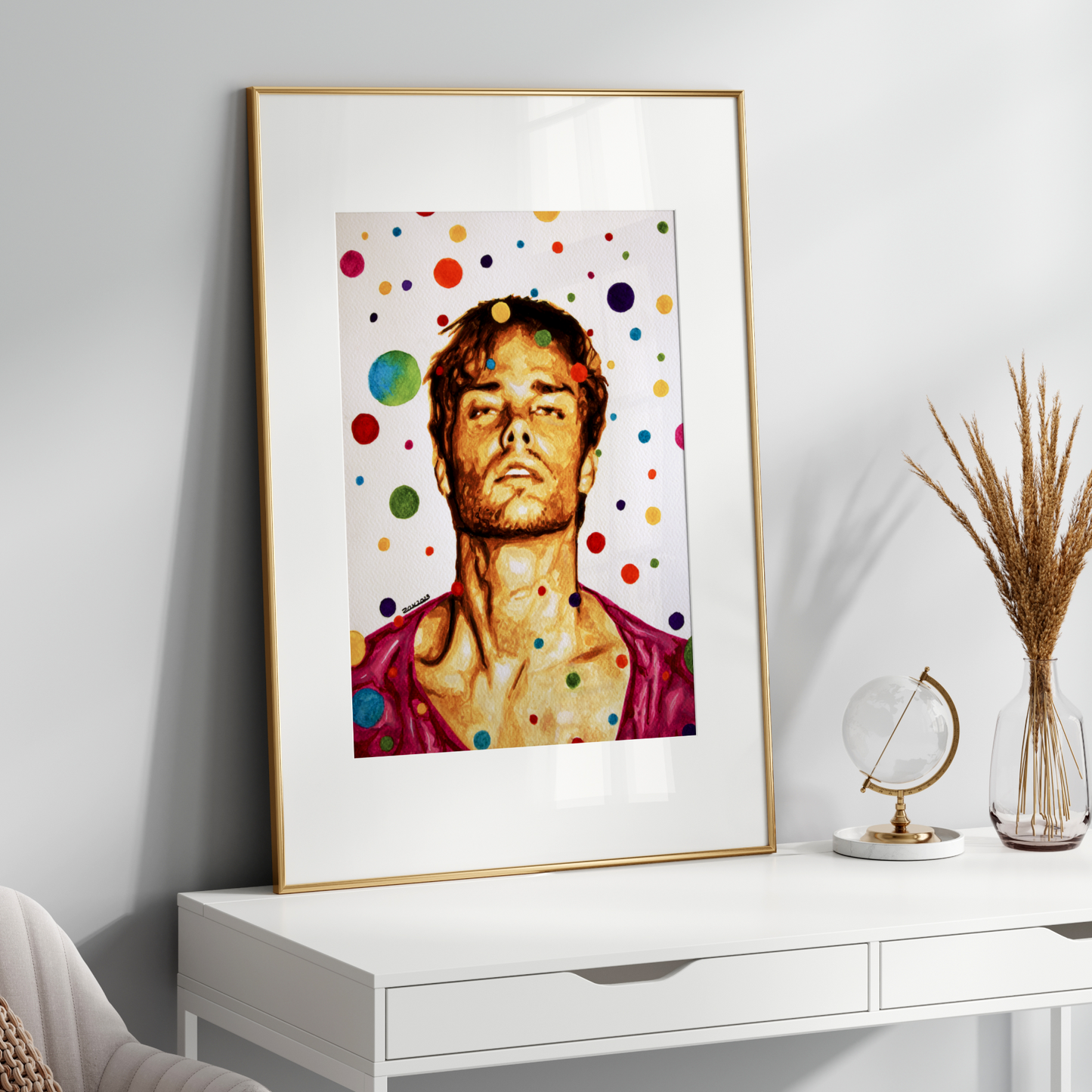 Framed artwork of a person with colorful polka dots on a white wall above a white console table.