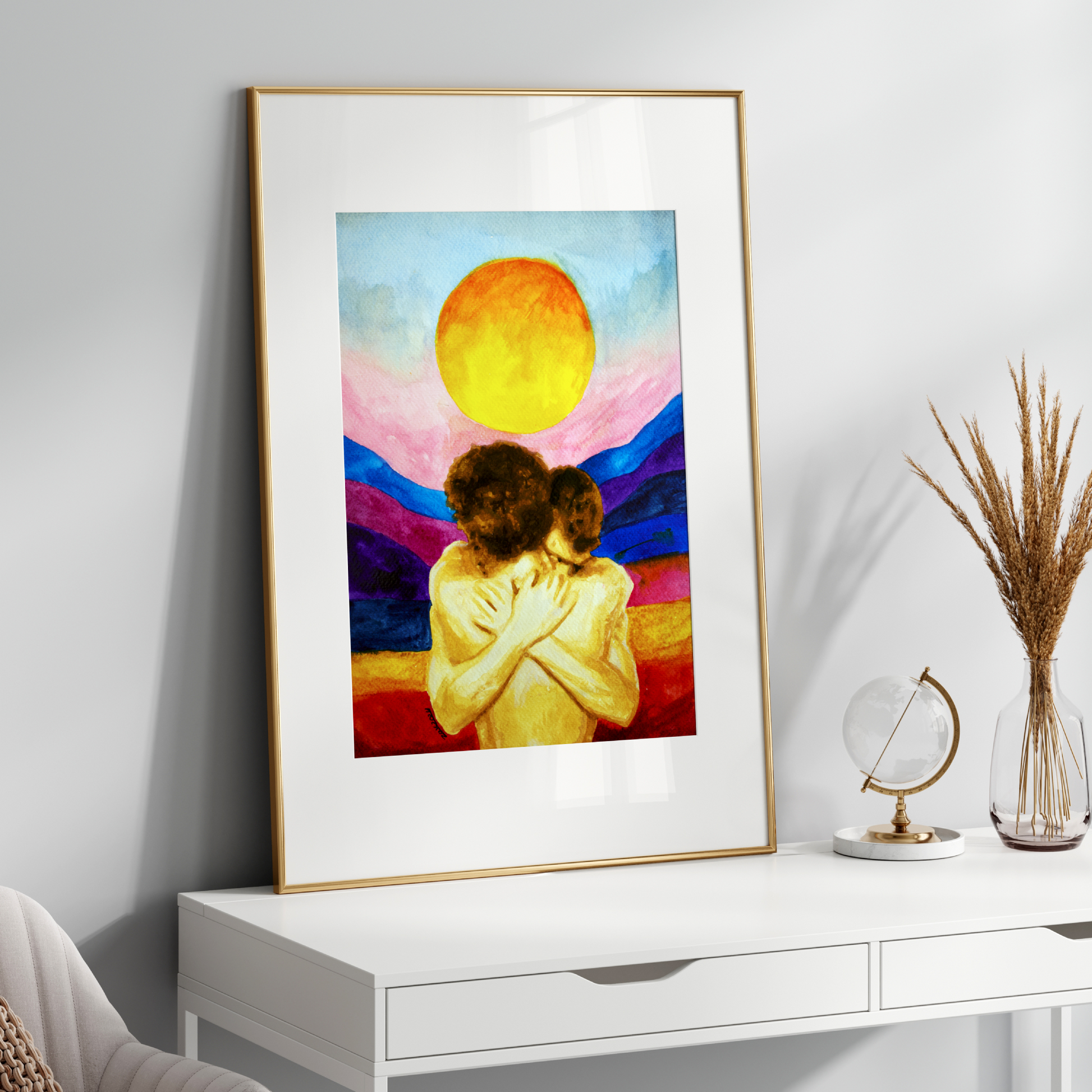 Framed artwork of two people hugging under a colorful sky with a sun, displayed on a white wall above a white console table.