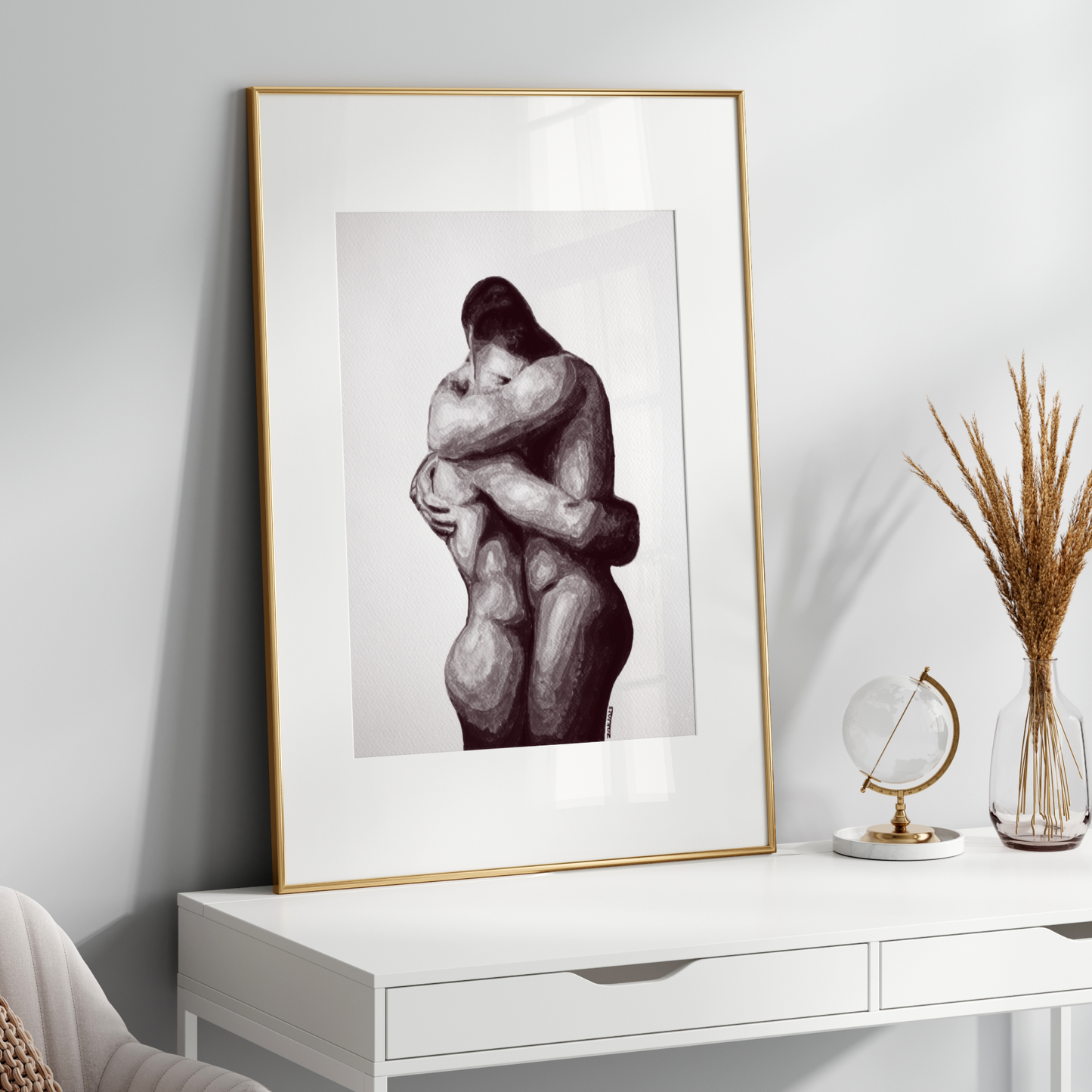 Framed black and white artwork of two embracing figures on a white console table.