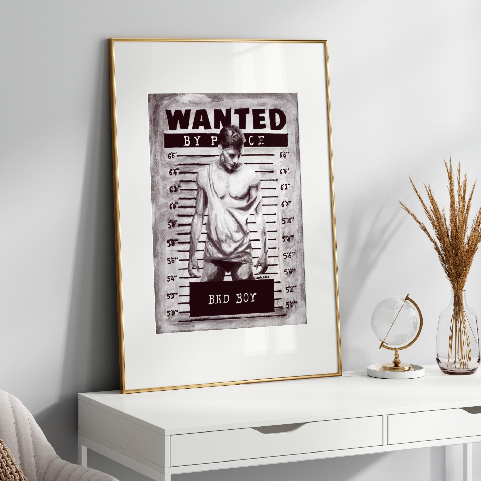Framed 'Wanted' poster on a white wall above a white desk with decorative items.