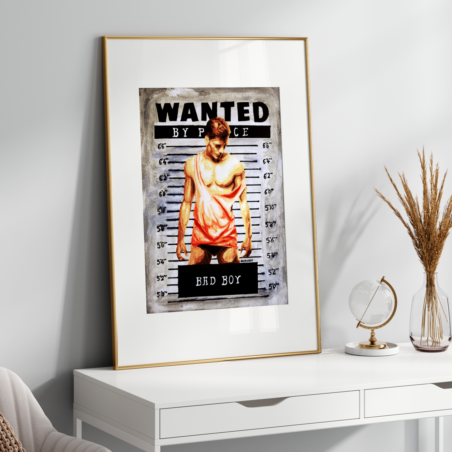 Framed 'Wanted' poster on a white wall above a white desk with decorative items.