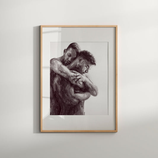 A black and white print of a same-sex couple embracing, framed in a light wood frame.
