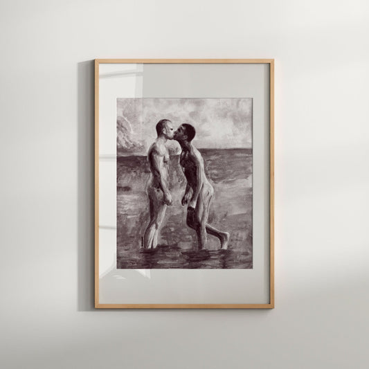 A black and white art print featuring a sensual nude gay couple kissing on the beach, framed in a light wooden frame.
