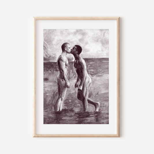 A black and white art print featuring a sensual nude gay couple kissing on the beach, framed in a light wooden frame.